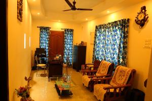 a living room with chairs and a ceiling fan at Heather Home Stay in Cochin