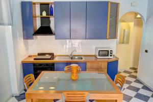 a kitchen with blue cabinets and a table with a vase on it at Apartment Tysandros in Giardini Naxos