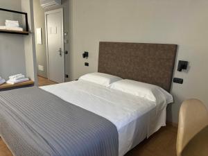 a bedroom with a large white bed and a chair at RE Versiliana Junior-House in Marina di Pietrasanta
