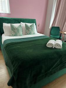 a green bed with two towels on top of it at The Lily Pad near Poole Dorset Self contained private entrance and free parking in Poole