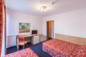 a hotel room with a bed and a desk with a computer at Семеен Хотел Опера in Burgas