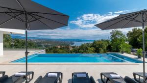 a swimming pool with chairs and umbrellas at Villa Gabi by Villas Holiday in Donji Rukavac