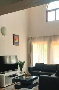 Una sala de estar con un sofá y un televisor. en Unique Stay- 1km to Monte Casino, en Sandton 4 fotos más