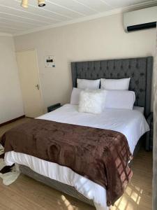 1 dormitorio con 1 cama grande y cabecero gris en Unique Stay- 1km to Monte Casino, en Sandton