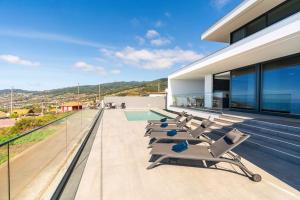 a group of lounge chairs on the roof of a house at Villa Lunarenzo seaview, Pool, AC, parking in Calheta
