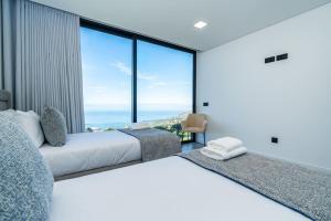 two beds in a room with a view of the ocean at Villa Lunarenzo seaview, Pool, AC, parking in Calheta +71 photos