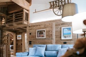 a living room with a blue couch and wooden walls at Chalet Mornà in San Martino in Badia