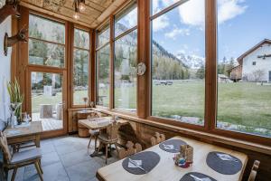 a dining room with large windows and a view of a field at Chalet Mornà in San Martino in Badia