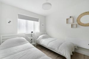 a white bedroom with two beds and a window at Mulberry in Bowness-on-Windermere