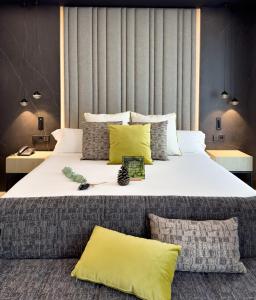 a bedroom with a large white bed with yellow pillows at Hotel Regina in Madrid