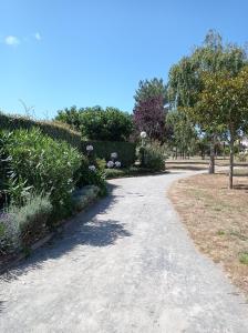 a gravel path in a park with trees and flowers at Studio l'Oasis - Piscine, plage de La Baule 10 min in Guérande +30 photos