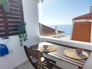 una mesa con dos sombreros y dos tazas en un balcón en Apartment Oceans Window, en Ericeira