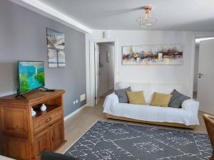 Una sala de estar con un sofá blanco y un televisor. en Apartment Oceans Window, en Ericeira
