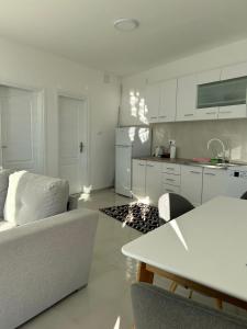 a white living room with a couch and a kitchen at Holliday Tivat in Peani