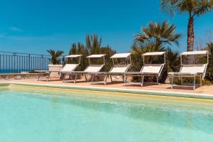 un gruppo di sedie a sdraio e una piscina di Villa con Piscina 150mt dal Mare 8 Posti OA ad Alcamo