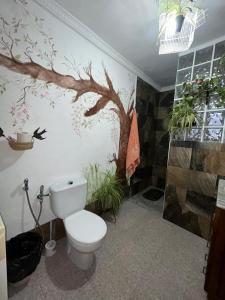 a bathroom with a toilet and a tree mural on the wall at Cueva de la abuela in Los Carriones +54 photos