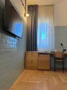 a room with a desk and a television on a wall at Re Versiliana Hotel in Marina di Pietrasanta