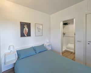 une chambre blanche avec un lit bleu et un miroir dans l'établissement Top Lacus-by Goccia di Lago, à Desenzano del Garda