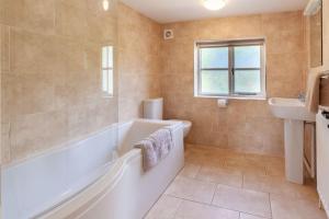 The Cow Barn - Norfolk Cottage Agency في Banningham: حمام مع حوض استحمام ومغسلة +33 صورة
