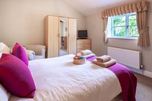 The Cow Barn - Norfolk Cottage Agency في Banningham: غرفة نوم مع سرير أبيض كبير مع وسائد أرجوانية