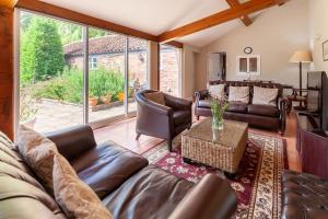 The Cow Barn - Norfolk Cottage Agency في Banningham: غرفة معيشة بأثاث جلدي ونافذة كبيرة