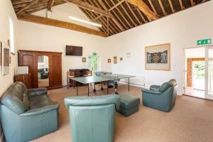 The Cow Barn - Norfolk Cottage Agency في Banningham: غرفة معيشة مع طاولة تنس وكراسي