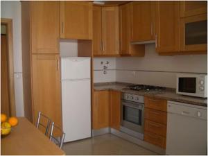 a kitchen with a white refrigerator and wooden cabinets at Akisol Albufeira Aqua II in Albufeira