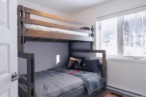 ein Schlafzimmer mit zwei Etagenbetten und einem Fenster in der Unterkunft Modern Mont Blanc Ski in Ski out Townhouse in Saint-Faustin