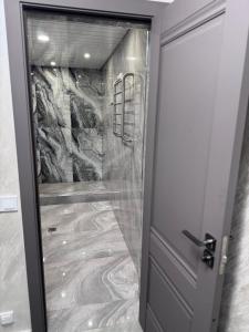 a walk in shower with a glass door at On The Way Apartment in Getapʼ