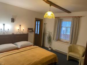 a bedroom with a bed and a chair and a window at Chata Paperule in Horní Maršov