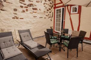 un patio con sillas, una mesa y una pared en Eulenhaus, en Ediger-Eller 20 fotos más