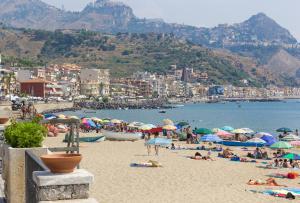 een groep mensen op een strand met parasols bij Apartment Tysandros in Giardini Naxos