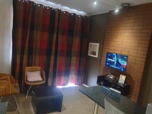 a room with a table and a tv and a curtain at THEE BnB in Johannesburg