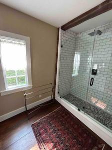 a bathroom with a shower with a window and a rug at The Doctor 1781 House on the Litchfield Green in Litchfield +35 photos