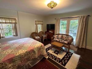 a bedroom with a bed and a chair and windows at The Doctor 1781 House on the Litchfield Green in Litchfield