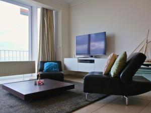 un salon avec un canapé et une télévision dans l'établissement Le Channel - Appartement moderne vue mer & deux chambres à Koksijde, à Coxyde