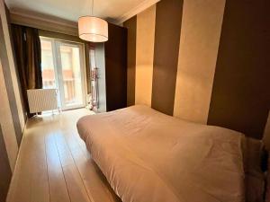 une chambre avec un lit blanc et une fenêtre dans l'établissement Le Channel - Appartement moderne vue mer & deux chambres à Koksijde, à Coxyde