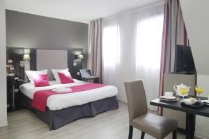 een hotelkamer met een groot bed en een tafel en stoelen bij Odalys City Strasbourg Green Marsh in Straatsburg