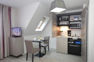 a small kitchen and dining room with a table and chairs at Odalys City Strasbourg Green Marsh in Strasbourg