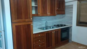 a kitchen with wooden cabinets and a sink at Appartamenti Manuela in Cala Gonone +11 photos