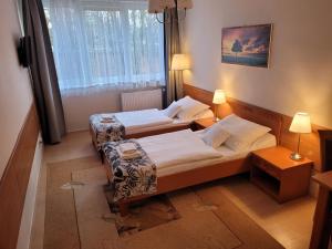 two beds in a small room with two lamps at Hotel Olimp in Chojnice