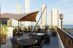 eine Terrasse mit Tischen und Stühlen auf dem Balkon in der Unterkunft Hotel Bahía Suites in Panama-Stadt