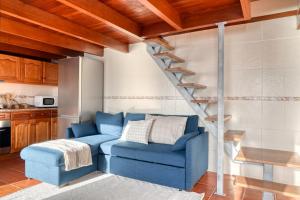 a living room with a blue couch and a staircase at Ocean View Cottage a Home in Madeira in Fajã da Ovelha