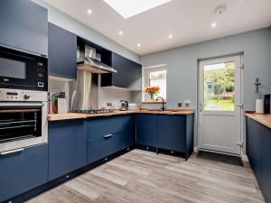 a large kitchen with blue cabinets and a window at 2 Bed seafront cottage in Portpatrick in Portpatrick