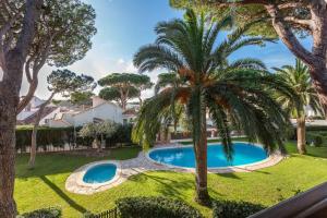 an image of a swimming pool in a yard with palm trees at Apartamento Gisela in L'Escala