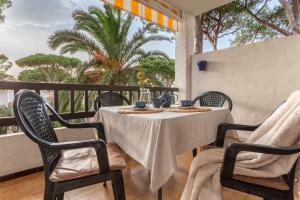 a table and chairs on a balcony with palm trees at Apartamento Gisela in L'Escala