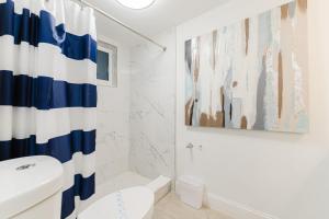 a white bathroom with a blue and white shower curtain at Elegant Escape! in Boca Raton +28 photos