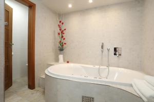 baño con bañera y jarrón de flores rojas en Hotel Pod Věží, en Strážnice