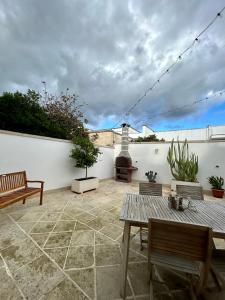 a patio with benches and a fireplace on a white wall at La Maison de Nicole 2 in Carmiano