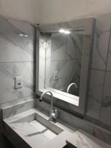 un bagno con lavandino e specchio di Pousada Samreny a Maracanã